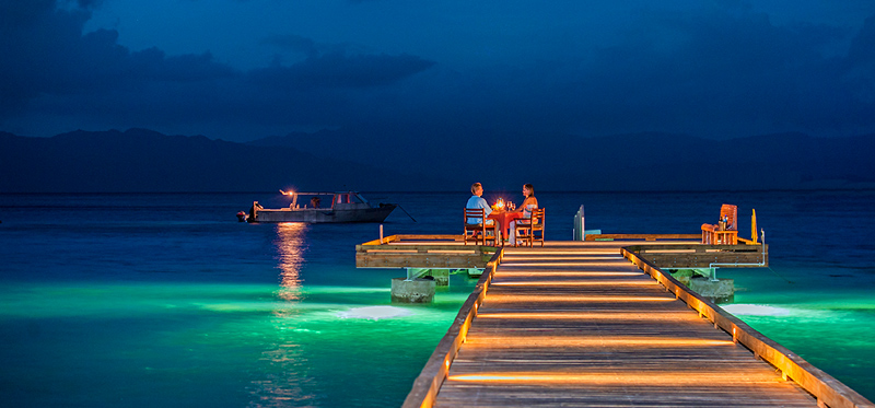 Couple dining on pier at Jean-Michel Cousteau Resort Fiji resort