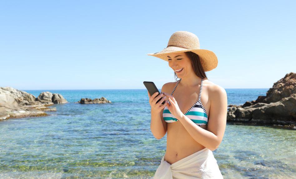 Tourist woman using phone at the beach